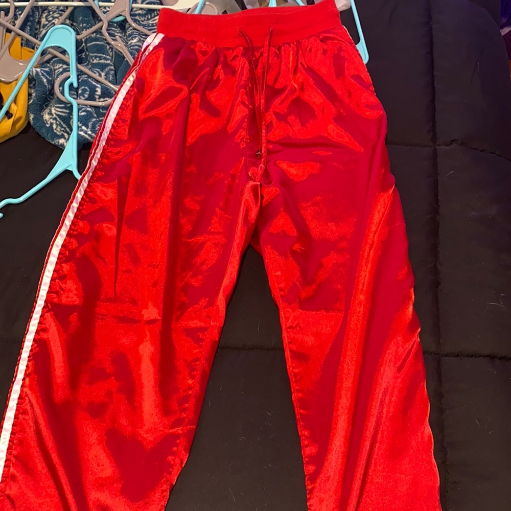 Red satin track pants with two white stripes on each side
